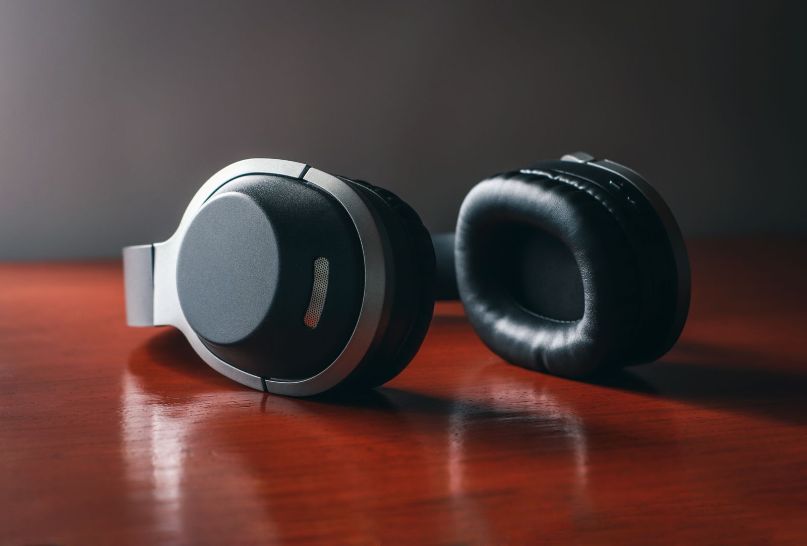 Close-up of black and gray over-ear wireless headphones resting on a wooden desk
