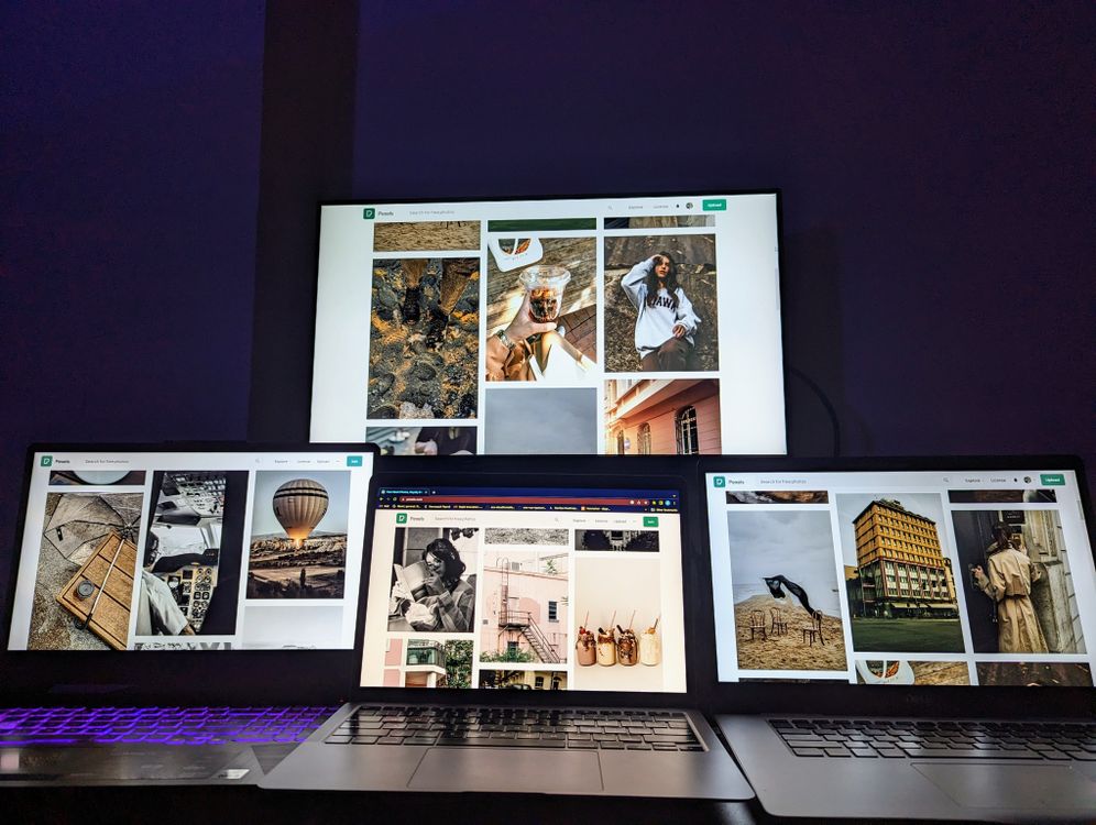 Multiple laptop and monitor screens glowing in a dark tech environment